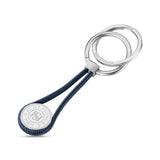 Silver-toned keyring with two rings, a dark blue coiled cord, and a silver-toned coin charm engraved 'SAINT HONORE PARIS'.