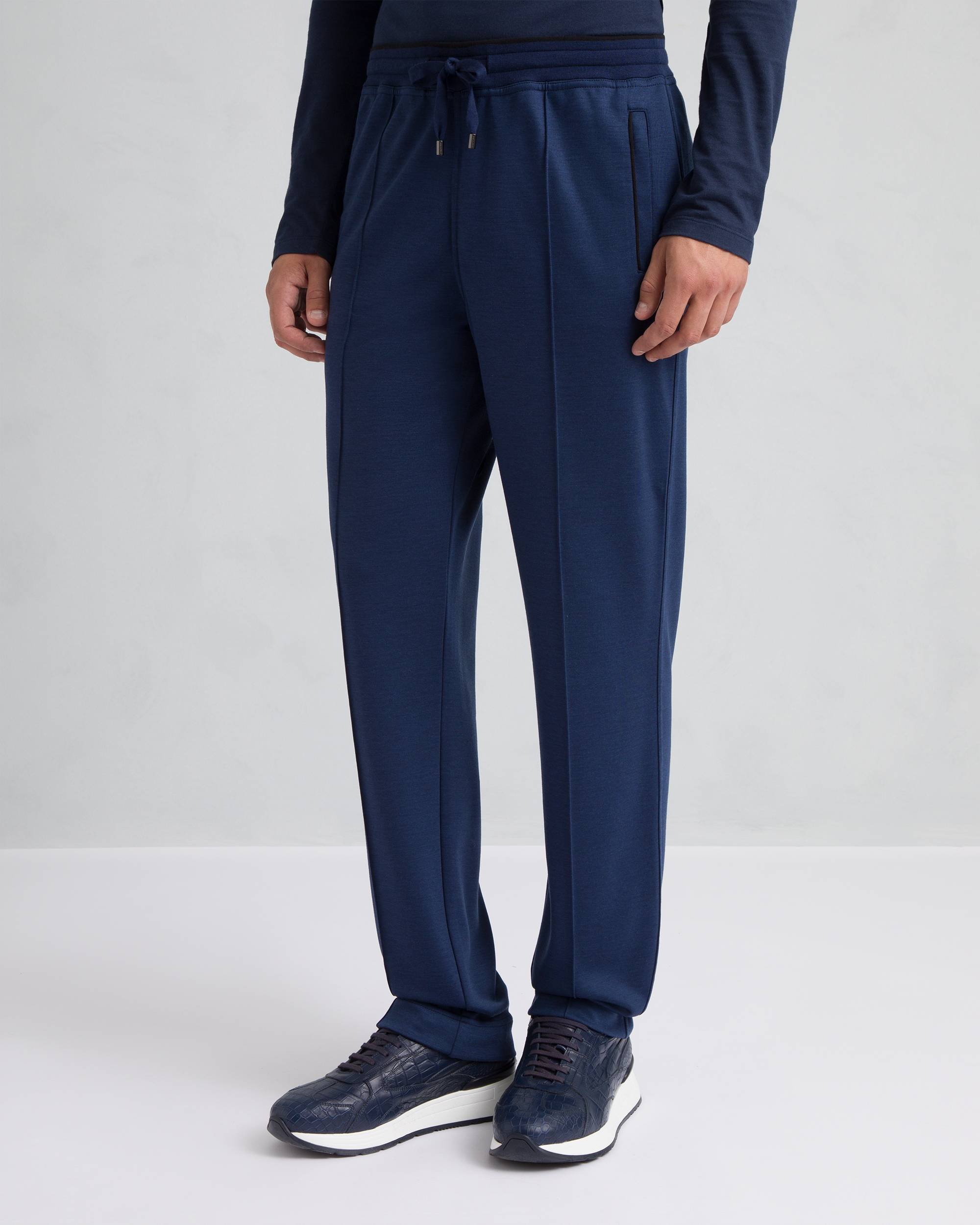 Navy blue men's relaxed-fit trousers with a drawstring waist, silver-toned metal tips, and vertical front leg seams.