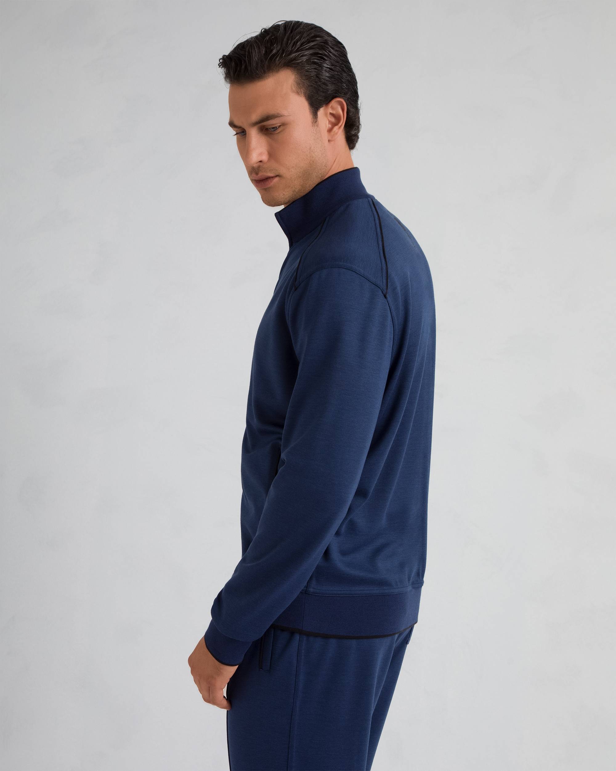 Navy blue sweater with a stand-up collar, front zipper, ribbed cuffs and hem, and black piping details.