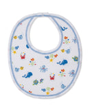 White baby bib with multicolor sea creature print, blue zigzag trim, and a snap button closure.