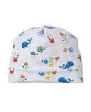 White baby beanie hat with a multicolor print of whales, crabs, turtles, fish, octopuses, and starfish.