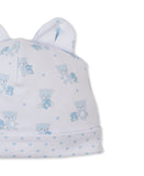 White baby hat with two ears, light blue teddy bear and star print, and a folded brim.