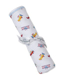 White blanket with multicolor airplane print, red, yellow, and blue planes. Rolled, tied with a white 'kissy kissy' ribbon.