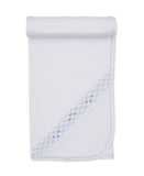 White knit baby blanket with a light blue embroidered diamond pattern and darker blue dots along one edge, and light blue sti