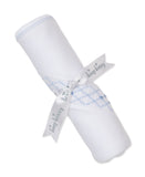 White blanket, rolled, with blue smocking in a diamond pattern and light blue stitched trim. A white 'kissy kissy' ribbon is