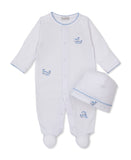White baby sleepsuit with blue scalloped trim and whale embroidery, paired with a matching white hat.