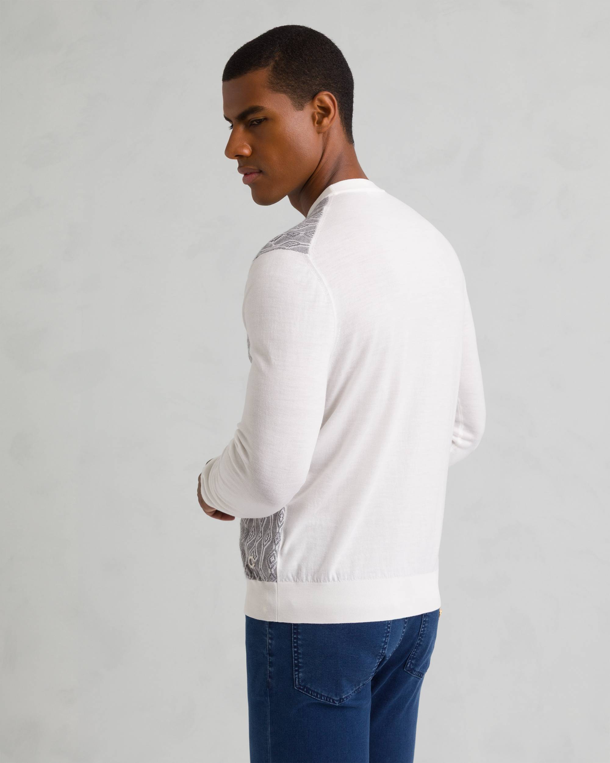 White fine-knit crew neck sweater with gray patterned panels on shoulders and sides, ribbed cuffs and hem.