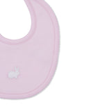 Light pink baby bib with a white embroidered bunny on the left and white scalloped trim along the edge.