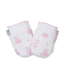 Pair of white baby mittens with a pink teddy bear and paw print pattern, featuring pink scalloped cuffs and a brand tag.