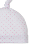 White newborn hat with an all-over pattern of small pink hearts, a folded brim, and a knotted top.
