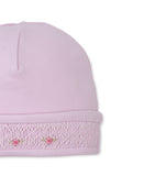 Light pink garment detail with a white smocked band featuring embroidered pink roses and gold-toned stems.