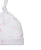 White baby knot hat with an all-over pink print of stars, suns, moons, and clouds. It has a folded brim.