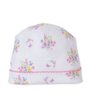 White baby beanie with multicolor floral bouquets and butterflies, featuring a pink scalloped trim on the brim.