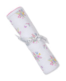 White blanket with multicolor floral bouquets and pink butterflies, rolled up and tied with a 'Kissy Kissy' ribbon. Pink scal