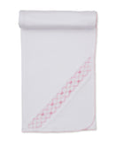White knit blanket with a pink smocked embroidery band featuring bow motifs and a pink scalloped edge trim.