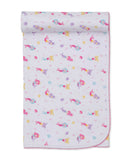 White blanket with multicoloured mermaid and sea-life pattern and pink scalloped edge, rolled at the top.