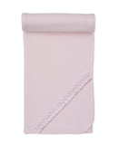 Pink knit baby blanket with rounded corners and a diagonal decorative trim featuring a white and pink patterned ribbon with a