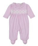 Pink sleepsuit with ruffled collar, white smocked chest panel with pink diamond pattern and bows, long sleeves, and footed de
