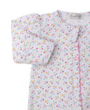 White sleepsuit with scattered pink, blue, and yellow heart print. Features gathered long sleeves and a pink ruffled front tr