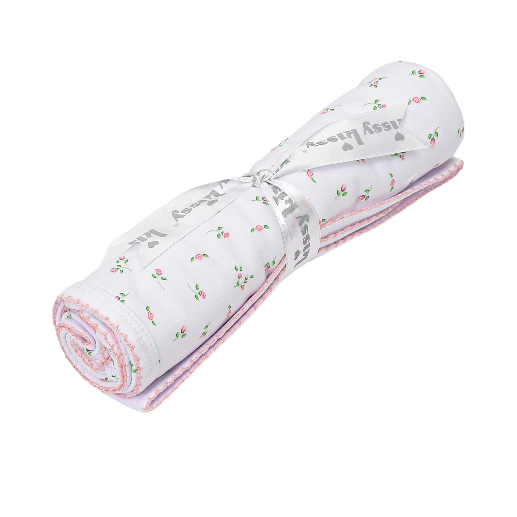 White rolled blanket with small pink rose and green leaf pattern, pink scalloped trim, tied with a white ribbon printed with