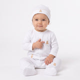 White footed sleepsuit with front snaps, tan scalloped trim, and three teddy bear embroideries. Includes matching beanie.