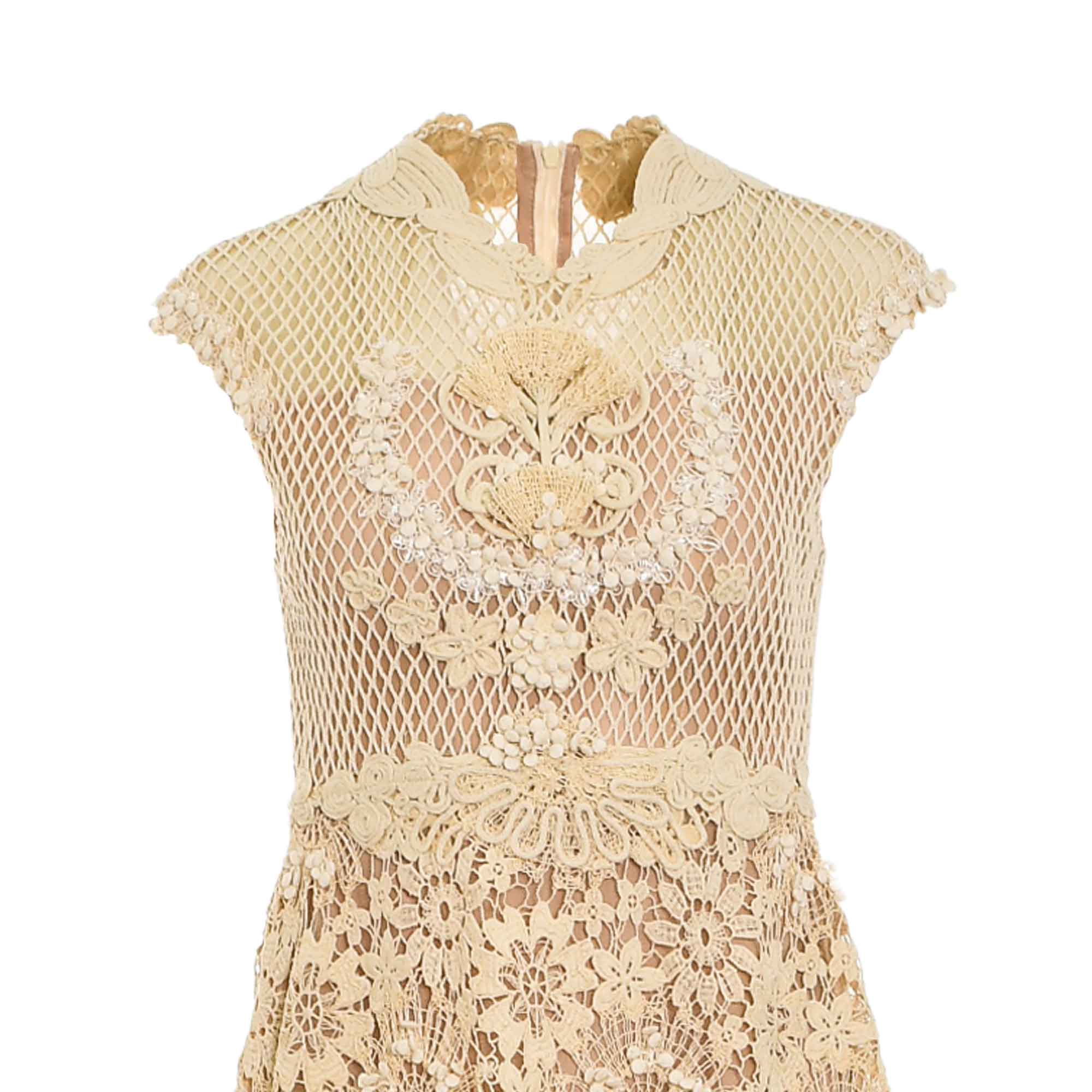 Beige dress with a high collar, short cap sleeves. Features a diamond-net bodice with intricate floral lace appliques and a f