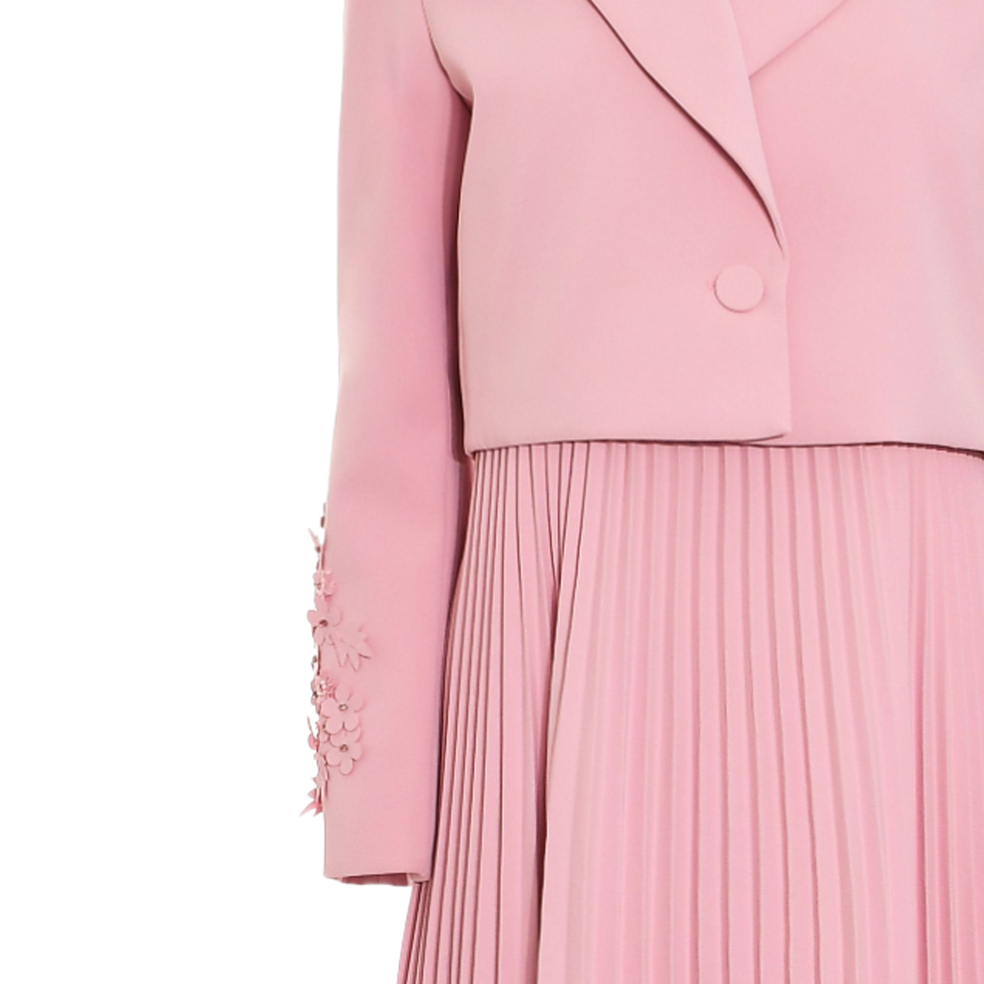 Pink dress with a cropped top, lapel collar, and single button closure. Pleated skirt and floral embellishments on the sleeve