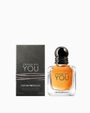 Dark gray box with "STRONGER WITH YOU" text next to a clear glass bottle with amber liquid and a black ribbed cap.