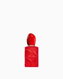 Red rectangular perfume bottle with a rounded red cap, gold-toned band, and raised 'Sì' lettering.