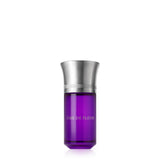A professional studio shot of the Liquides Imaginaires Âme de Fleur perfume. The bottle is a vibrant, translucent purple glass with a wide, brushed silver-toned metal cap. Next to it stands its tall, black textured presentation box, which features a white label band with "ÂME DE FLEUR" and the brand's logo in silver, set against a white background.