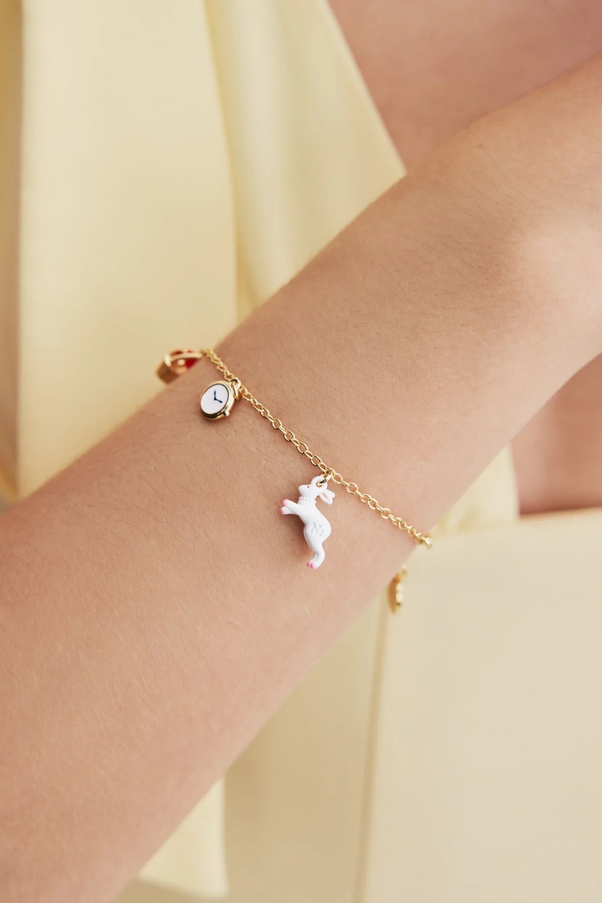 Les Néréides MULTIVERS Women's Delicate Bracelet Bracelet with a unicorn charm on a wrist against a light yellow background