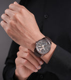 Lifestyle close-up shot of the Police watch PEWGB0092603 worn on a man's wrist over a black shirt, highlighting the matte brown IP case, dark gunmetal textured face, and genuine brown leather strap.