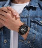 Lifestyle image of the Police watch PEWGF00814X2 with the brown leather strap worn on a man's wrist, coordinated with a casual blue denim jacket over a white t-shirt.