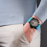 Lifestyle shot of the Police watch PEWGR0097804 on a man's wrist with his hand in his pocket, highlighting how the light blue silicone strap contrasts against a soft blue knit sweater and beige trousers.