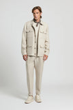 Beige pure linen Saharan jacket with a pointed collar, dark brown button front, and four button-flap patch pockets.