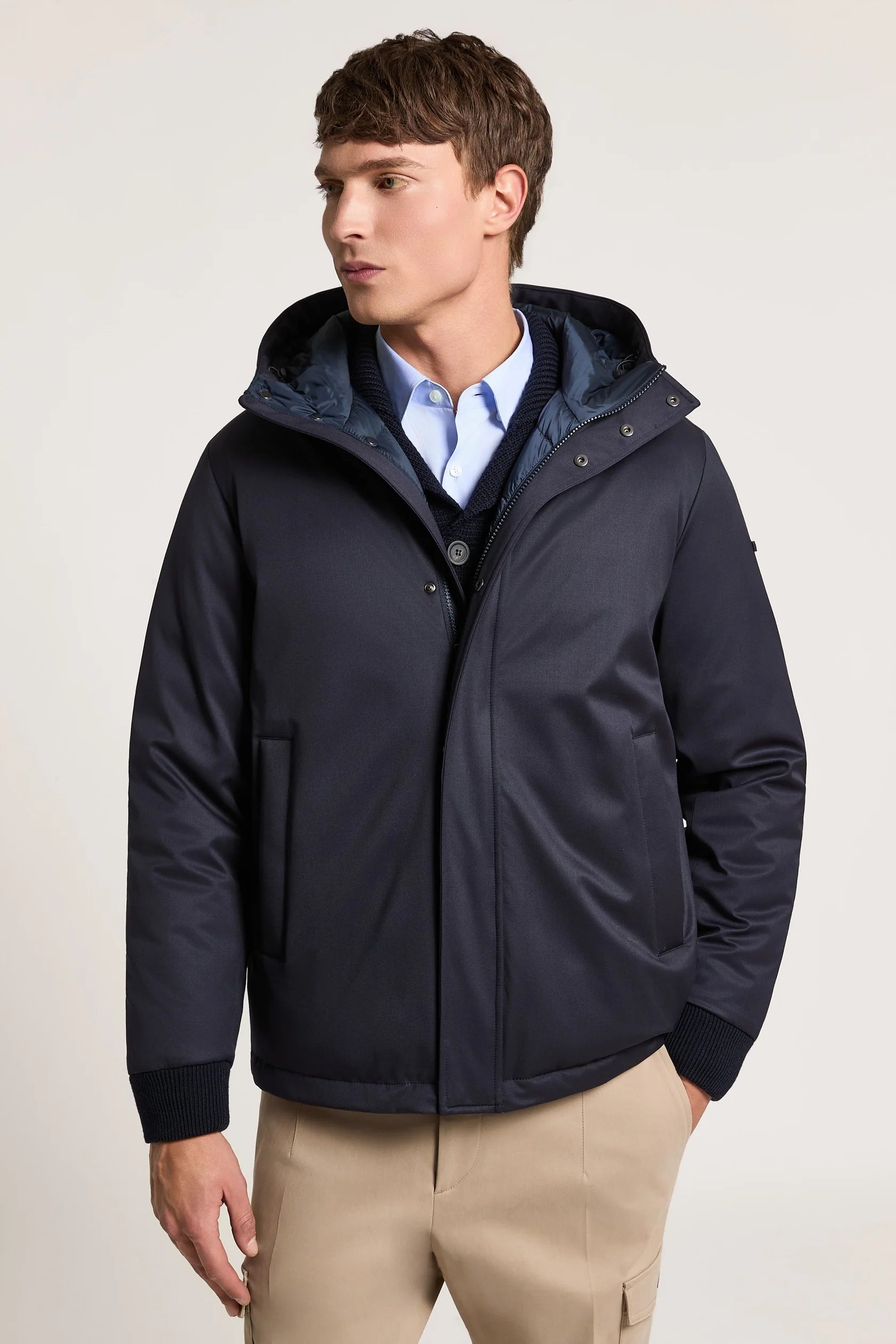 Smooth navy blue hooded jacket with ribbed cuffs. Features a quilted inner layer, snap-button placket, and slit pockets.