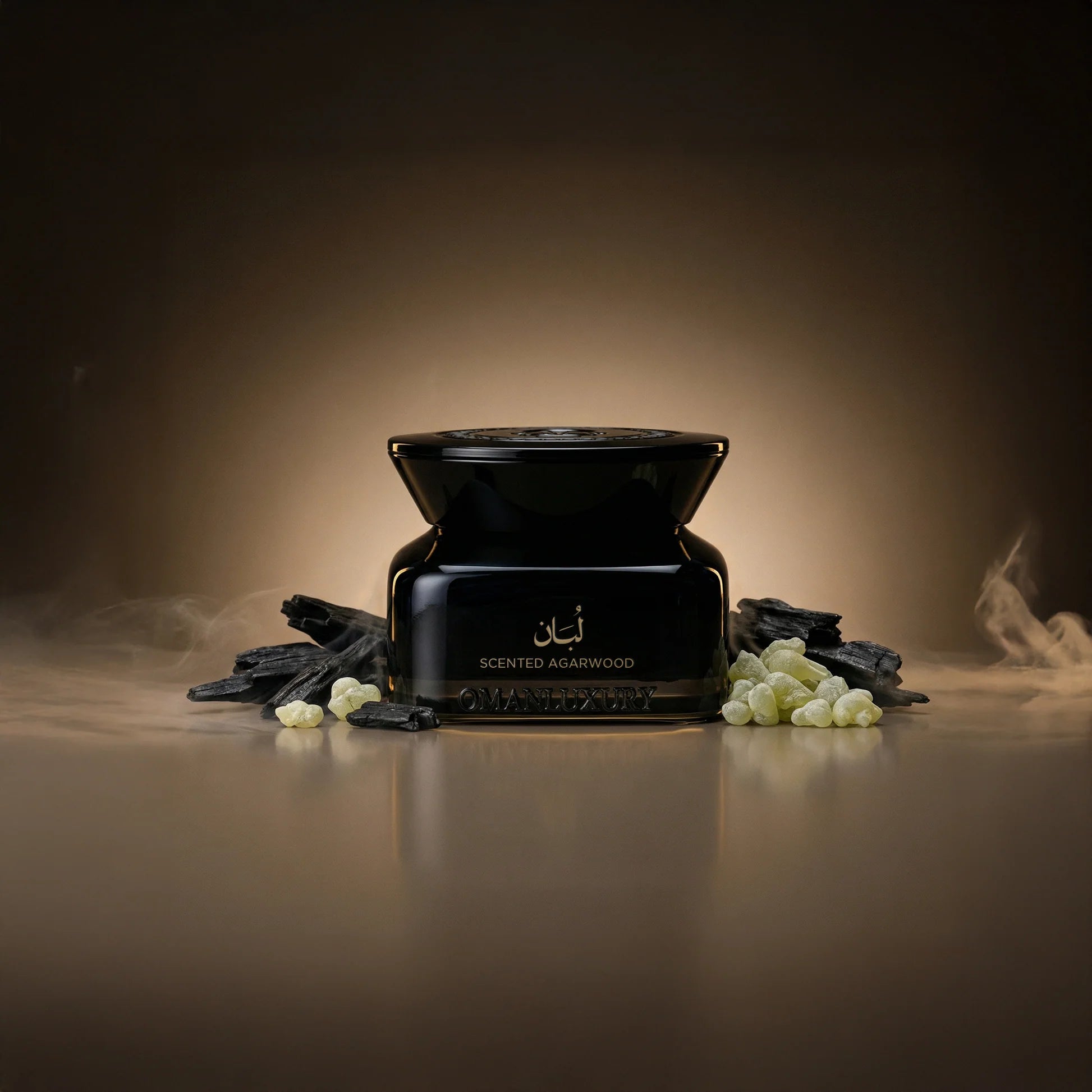 Black jar of scented agarwood with a decorative lid, surrounded by dark agarwood chips and light green frankincense resin.
