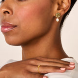 Gold-toned drop earring with a circular, textured stud and an irregular off-white pearl.