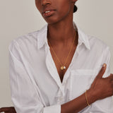 Yellow gold-toned necklace with a textured round disc pendant and an irregular white baroque pearl.