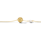 Gold-toned chain bracelet with a hammered disc charm featuring a clear stone, and an irregular white pearl.
