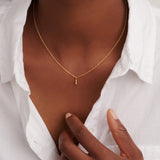 Delicate gold-toned necklace with a thin chain and a small pendant featuring three clear round stones vertically aligned.