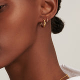 Gold-toned twisted hoop earring, half smooth and half encrusted with sparkling clear stones.