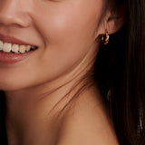 Gold-toned twisted hoop earring with one band embellished with small clear stones.