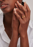 Gold-toned chain-link ring with two solid rectangular links flanking a central link paved with small, clear stones.