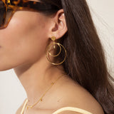 Gold-toned dangle earring with a flat round stud, a small clear marquise gem, and two concentric plain hoop rings.
