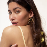 One gold-toned earring with a round stud, from which two concentric smooth hoops dangle.