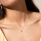 Thin gold-toned chain necklace with a small, textured, yellow gold-toned lemon-shaped pendant.