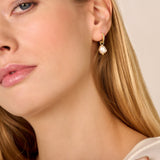 A single gold-toned hoop earring with small clear stones, featuring an irregular off-white pearl drop with a small gold-toned