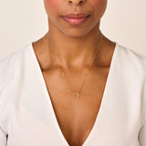 Delicate gold-toned chain necklace with a small, round, open circle pendant encrusted with clear stones.