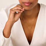 Gold-toned necklace with a thin chain and a small, textured open circle pendant.